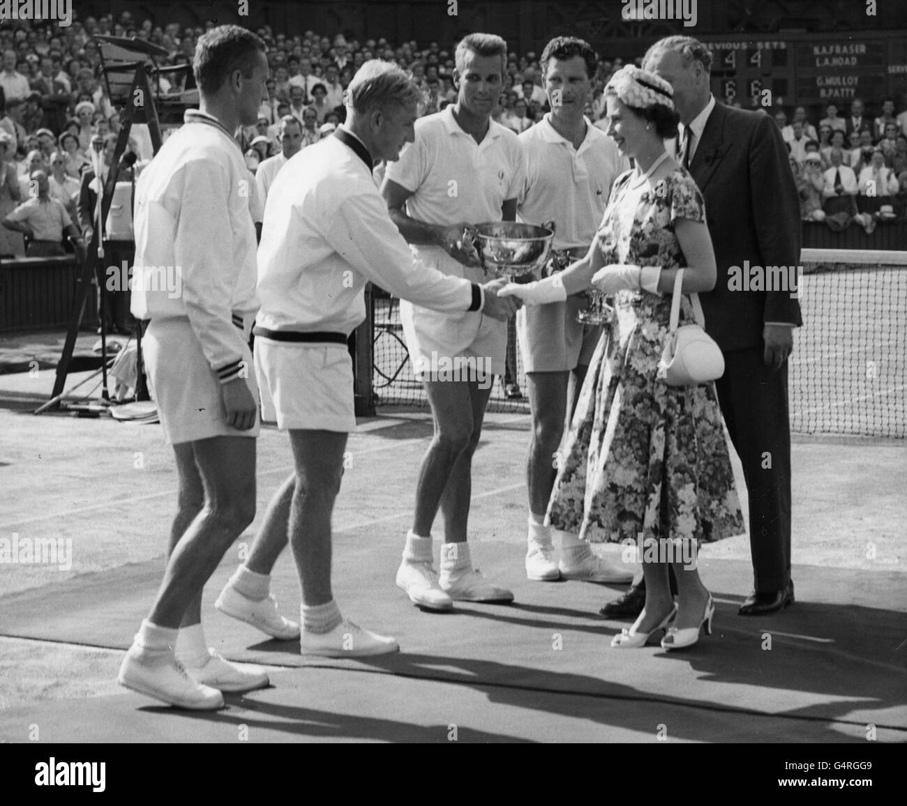 Nach dem Finale des Herrendoppel in Wimbledon überreicht die Queen den Gewinnern Gardner Mulloy und Budge Patty ihre Trophäe. Sie gratulierte dem australischen Lew Hoad, der im Doppel auf der Verliererseite war, zu seinem Sieg in den Herreneinzeln. Stockfoto