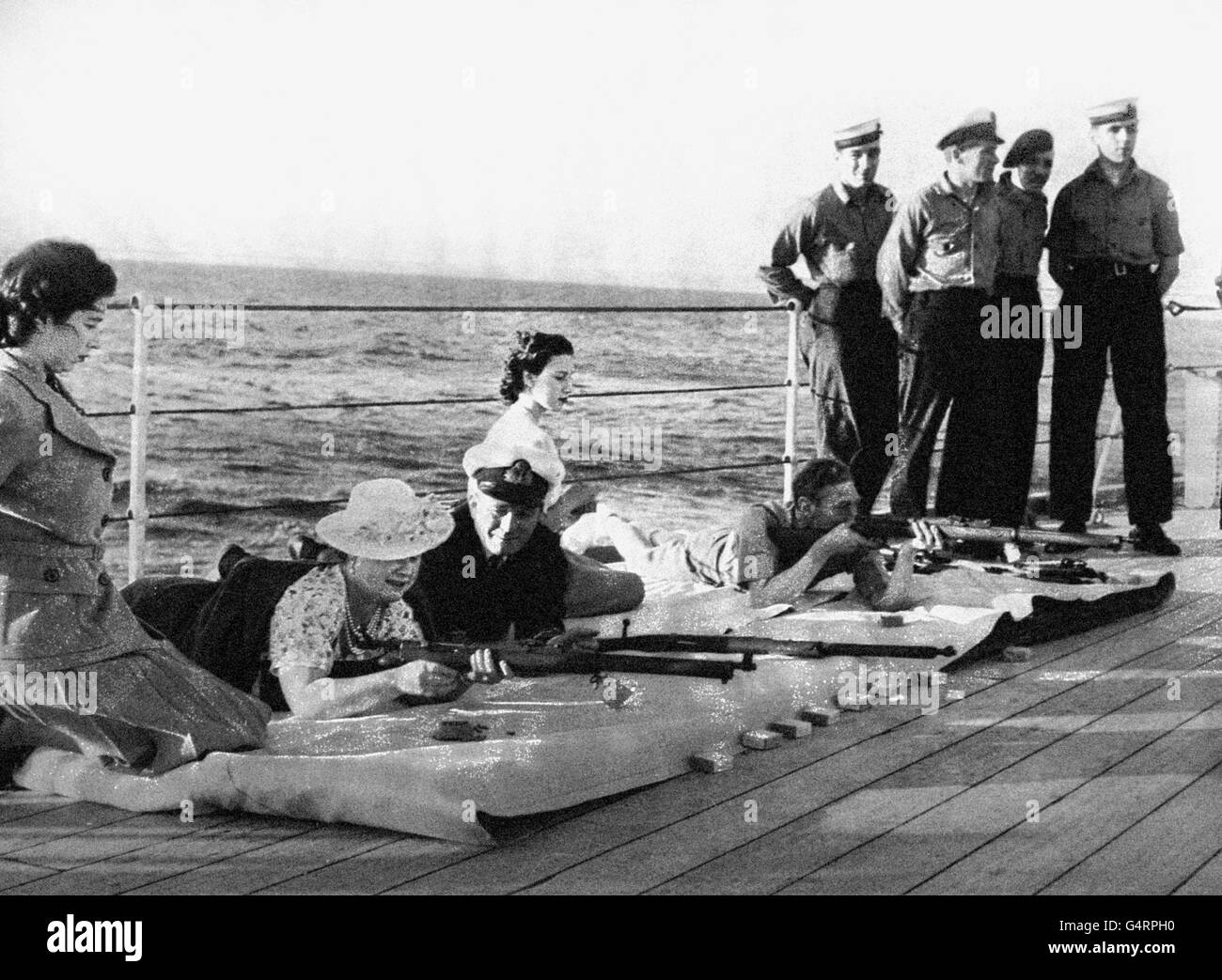 König George VI. Mit Königin Elizabeth, Prinzessin Elizabeth und Prinzessin Margaret auf dem Deck der HMS bei Gewehrübungen. Stockfoto