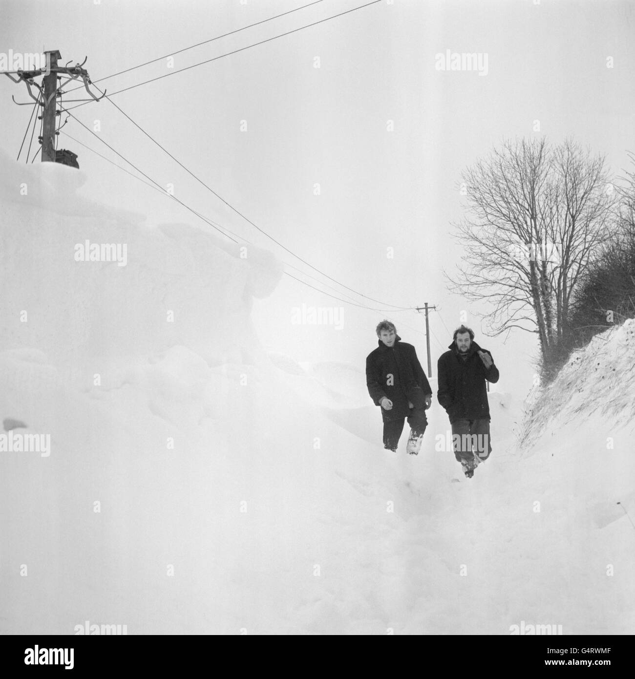 Zwei Männer arbeiten dort durch bis zu 8 Meter hohe Schneeverwehungen auf blockierten Straßen in der Nähe von Briantspuddle, Dorsetshire. Die Drifts waren das Ergebnis eines heftigen Schneesturms, der über Nacht Schnee über das Land fegte Stockfoto