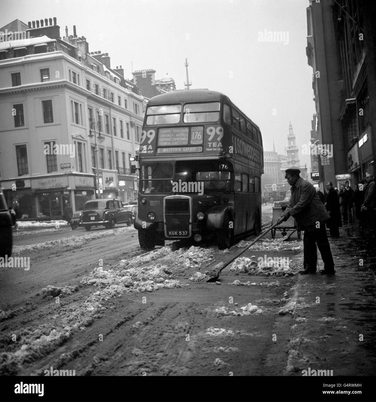 Ein Mann mit Schaufel reinigt den Strand of Slush in London nach einem heftigen Schneesturm, der Schnee über das Land gefegt hat. Stockfoto