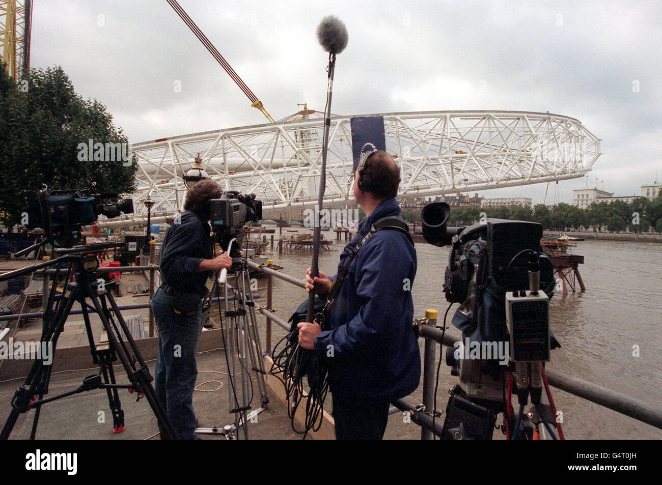 Eine Fernsehcrew sieht zu, wie das British Airways London Eye 10 Grad, etwa 100 Fuß, über der Themse in London angehoben wird, nachdem Ingenieure einen neuen Versuch gestartet haben, das Millenium-Riesenrad über den Fluss zu heben, einen Monat nachdem das letzte Angebot gescheitert war. * das Konstruktionsteam hofft, das Rad, das 1,500 Tonnen wiegt, in den nächsten zwei Tagen um 65 Grad anzuheben. Der neue Versuch begann, als die Arbeiter das Rad von den neun Stützplattformen befreiten, auf denen es ruht. Wenn alles nach Plan verläuft, wird erwartet, dass es bis zum Ende des Tages 30 Grad erreichen wird. Stockfoto