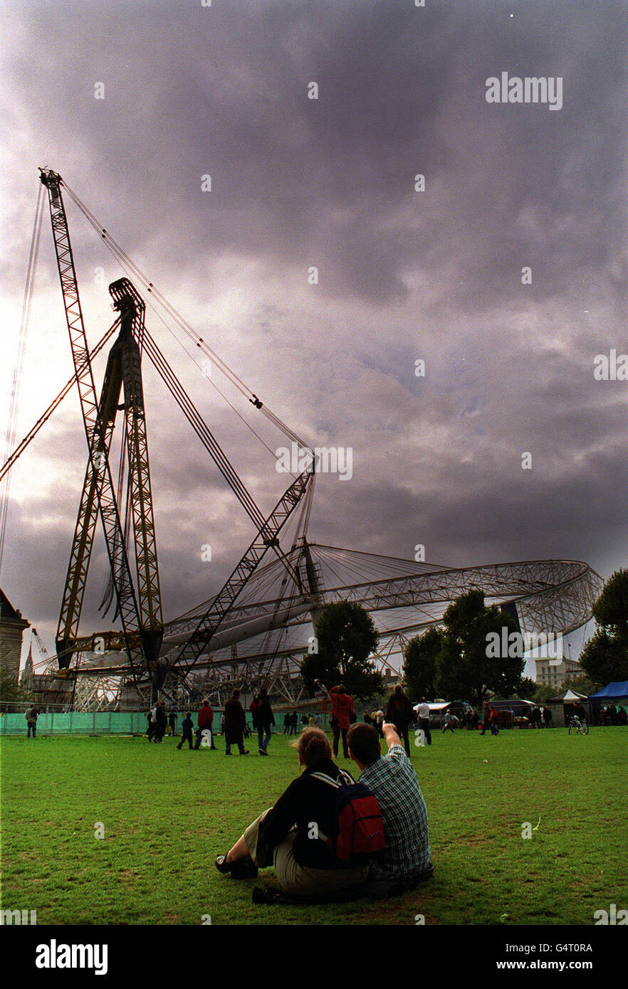 Ein Paar beobachtet, wie das London Eye von British Airways um 10 Grad, etwa 100 Fuß, über der Themse in London angehoben wird, nachdem die Ingenieure einen neuen Versuch gestartet haben, das Millenium-Riesenrad über den Fluss zu heben, einen Monat nachdem das letzte Angebot gescheitert war. * das Konstruktionsteam hofft, das Rad, das 1,500 Tonnen wiegt, in den nächsten zwei Tagen um 65 Grad anzuheben. Der neue Versuch begann heute Morgen, als die Arbeiter das Rad von den neun Stützplattformen befreiten, auf denen es ruht. Wenn alles nach Plan verläuft, wird erwartet, dass es bis zum Ende des Tages 30 Grad erreichen wird. Stockfoto
