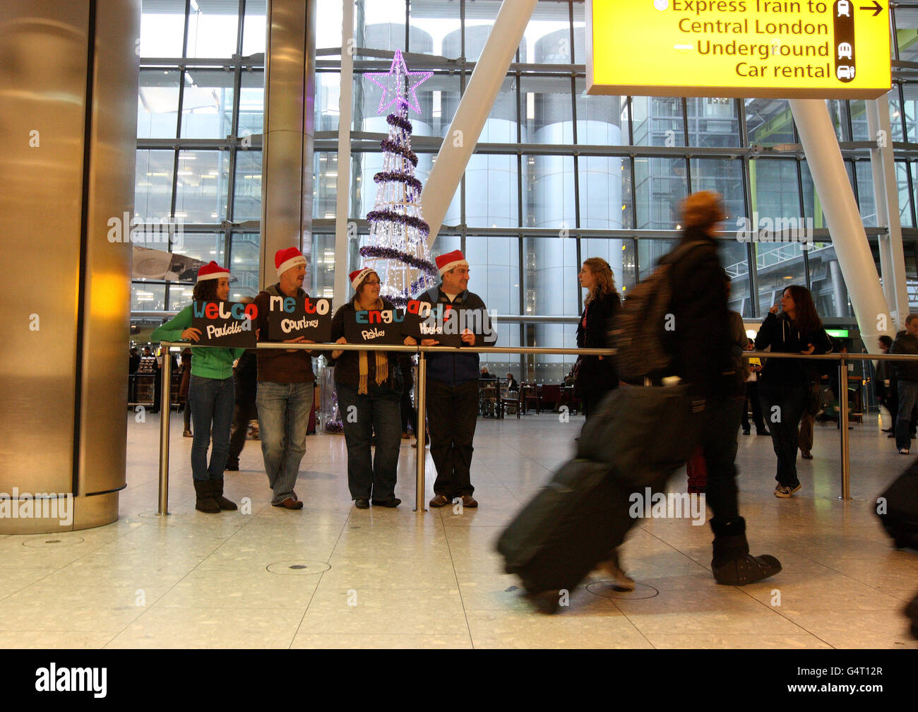 Freunde und Familienmitglieder warten auf einen ankommenden Passagier im Terminal 5, der Weihnachtsmützen trägt, während die Leute für die Weihnachtsfeiertage nach Hause fliegen. DRÜCKEN Sie VERBANDSFOTO. Bilddatum: Freitag, 23. Dezember 2011. Millionen von Menschen wurden erwartet, um die Straßen heute an dem, was erwartet wird, dass der geschäftigste Tag der Weihnachtsreise zu nehmen. Flughäfen und Häfen waren auch voll von Menschen, die die festliche Zeit im Ausland verbringen. Ein Sprecher der AA sagte, dass in der 24-Stunden-Zeit von gestern Abend bis heute Abend bis zu 18 Millionen Autos auf den Straßen sein würden. Siehe PA Story REISE Kurzurlaub. Foto Stockfoto