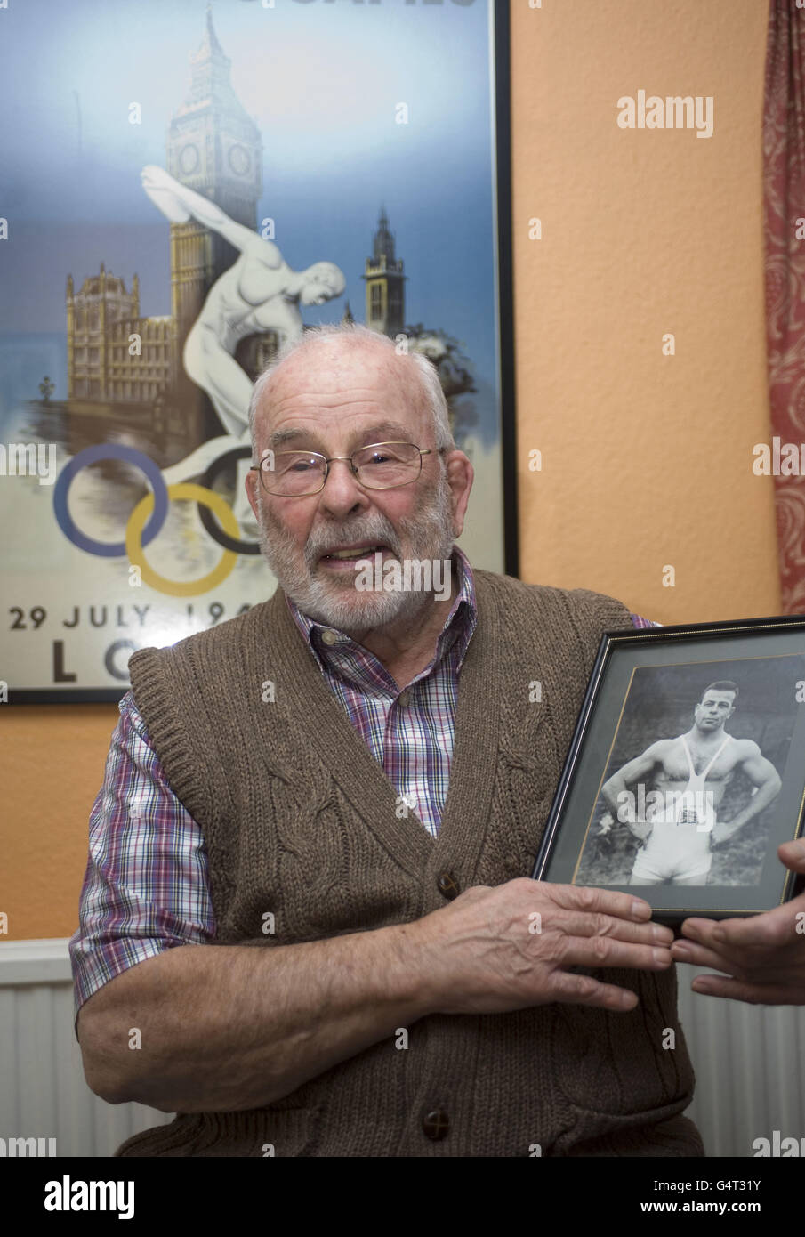 Der ehemalige olympische Ringer Ray Myland aus Leigh-on-Sea, Essex, der bei den Olympischen Spielen 1948 in London mit einem Bild von sich selbst bei den Olympischen Spielen 1952 in Helsinki teilnahm. Stockfoto