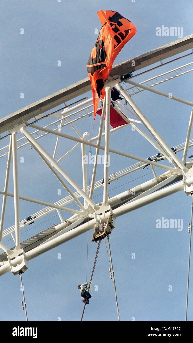 Ein Demonstrator entrollt ein Banner auf dem neu errichteten, 450 Meter hohen Millennium Wheel an der Themse. Bis zu zehn Aktivisten der baskischen Gruppe, Solidarios con Itoitz, und der indischen Gruppe, Narmada UK, entwichen der Sicherheit, bevor sie Banner enthüllten. * Sie sind gegen den Bau von Staudämmen im Baskenland in Spanien und in Indien. Das 1,500-Tonnen-Rad, offiziell als London Eye bekannt, wurde schließlich in eine aufrechte Position am Südufer der Themse gezogen. Es bietet einen spektakulären Blick über die Hauptstadt und soll am Millennium Eve eröffnet werden und mindestens fünf Jahre in Position bleiben. Stockfoto