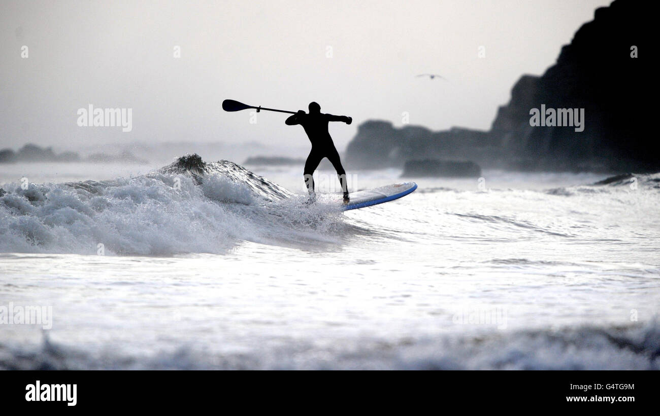 Ein Longboard Surfer genießt die Wellen in Longsands, Tynemouth, da die Prognostiker erwarten, dass das kalte Wetter bis Mitte nächster Woche andauern wird. Stockfoto
