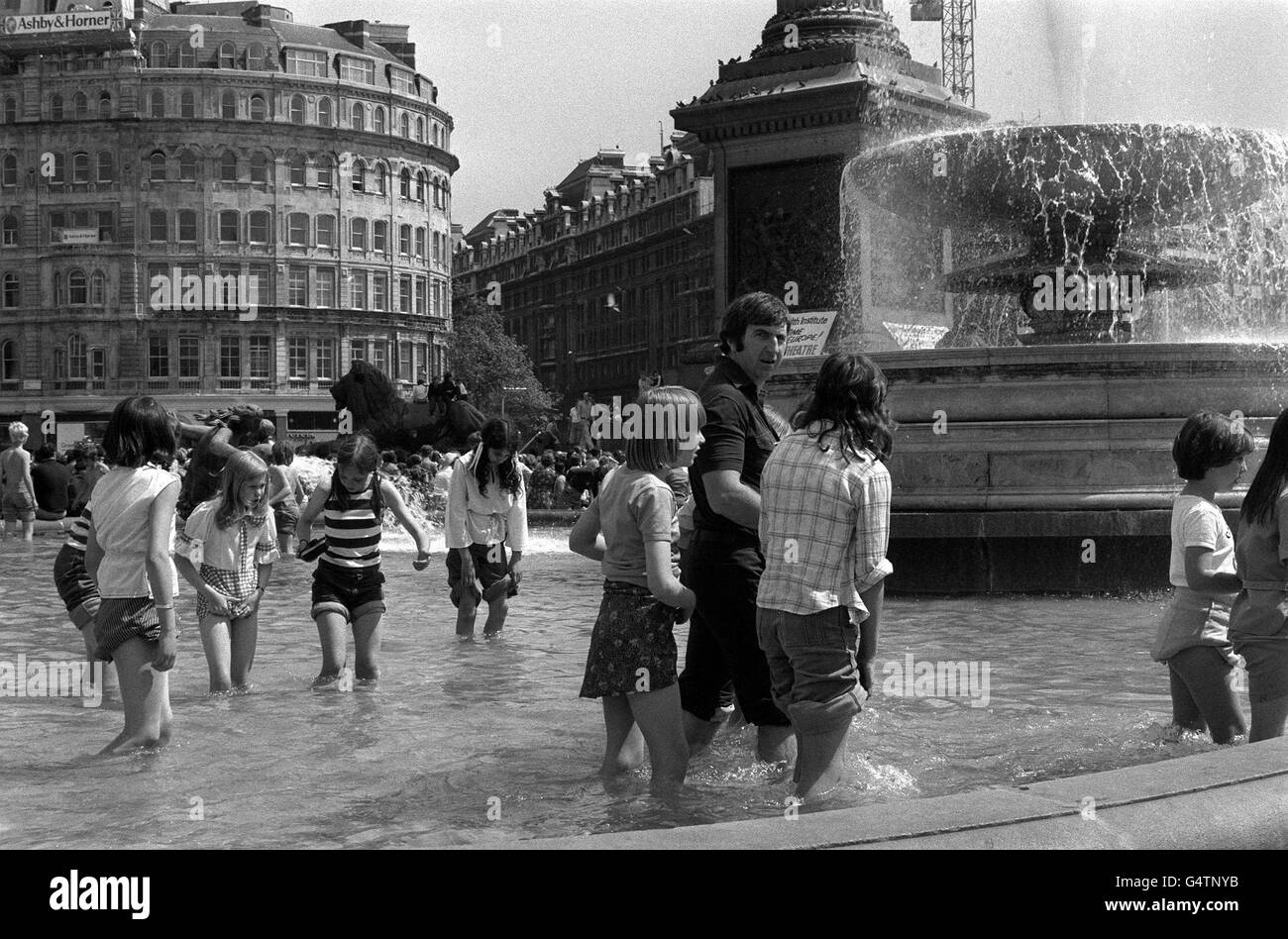 Kinder und Erwachsene nutzen den Brunnen am Tralgar Square, während sie sich im heißen Sommer abkühlen. Stockfoto