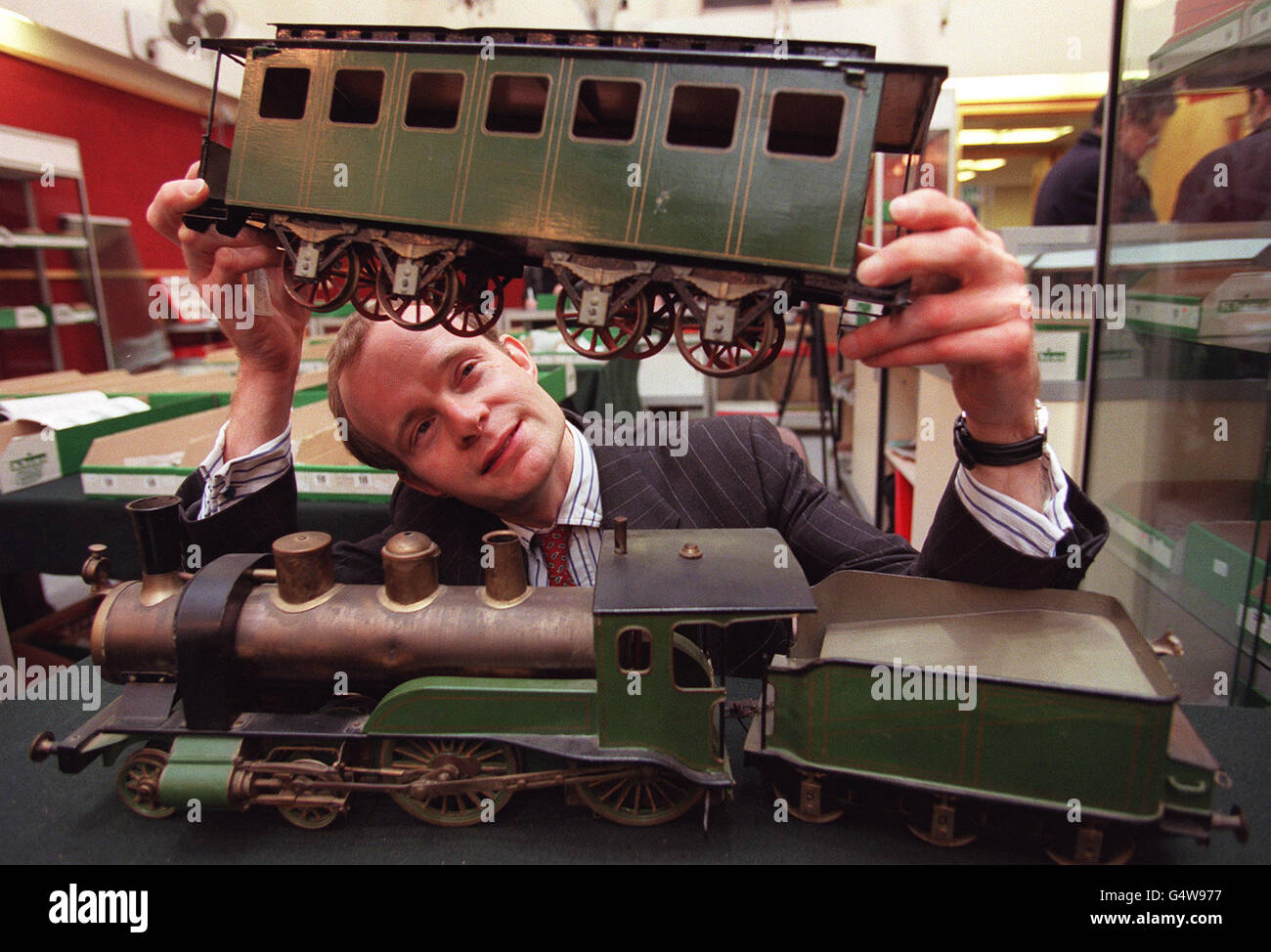 Christies Spielzeugeisenbahn-Spezialist Hugo Marsh untersucht einen äußerst seltenen Schoenner Gauge III-Dampfzug aus der Jahrhundertwende. Der Zug wird voraussichtlich zwischen 12,000 - 15,000 Uhr während einer Live-Internet-Auktion bei Christies abholen. *die Auktion findet am Montag, den 20. Dezember 1999, statt und ist die erste Auktion von Christie, die live im Internet stattfindet. Stockfoto