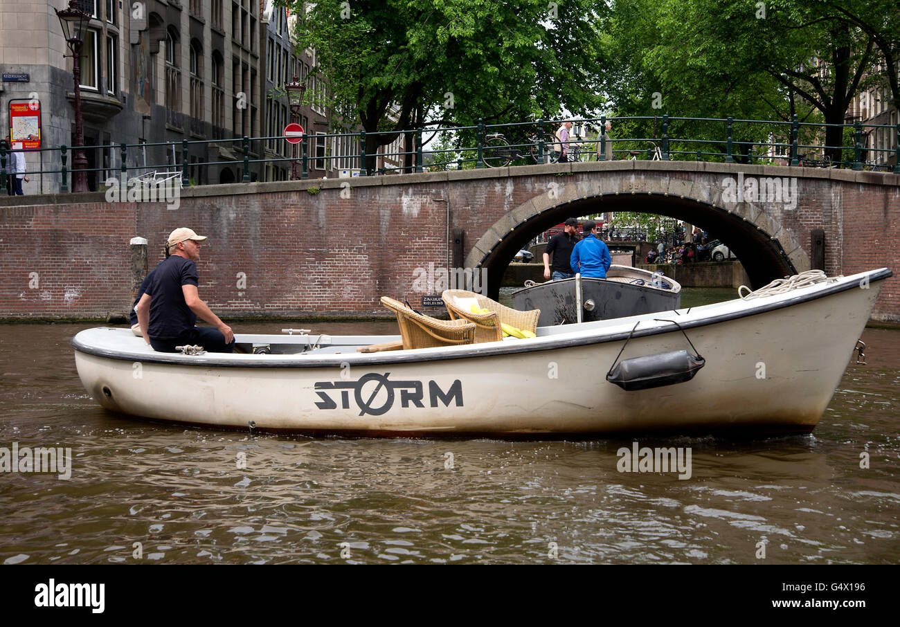 Boot wartet, durch eine gewölbte Brücke am Kanal in Amsterdam zu reisen. Stockfoto