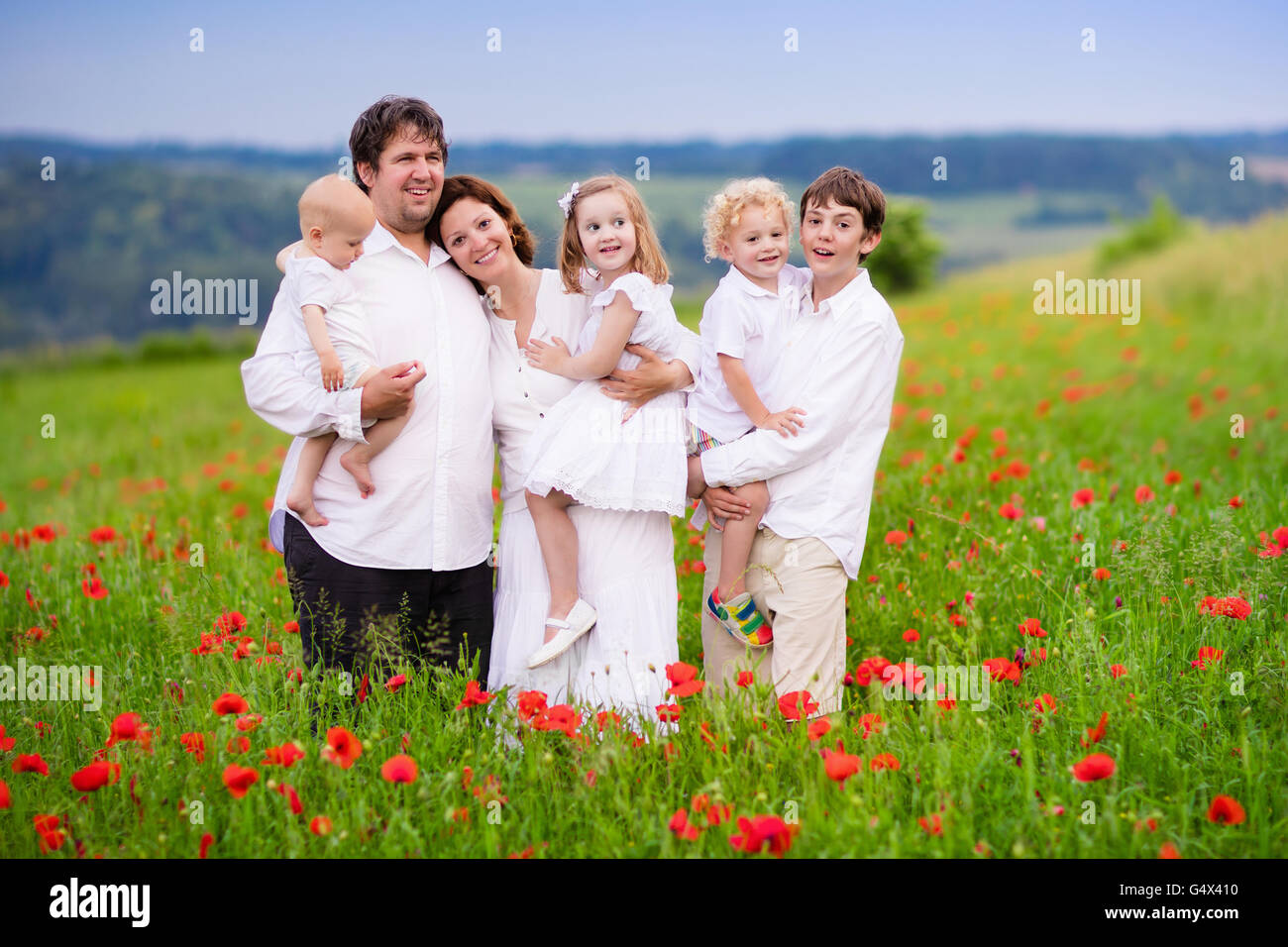 Große, glückliche Familie mit vier Kindern in roter Mohn Blumenfeld. Stockfoto