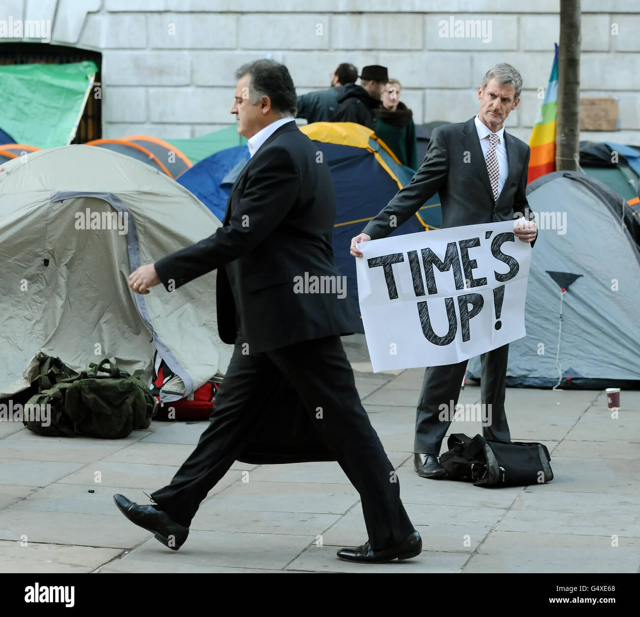 Büroangestellte passieren antikapitalistische Demonstranten, die vor der St Paul's Cathedral im Zentrum von London im Rahmen der "Occupy the London Stock Exchange"-Demonstration lagerten. Stockfoto