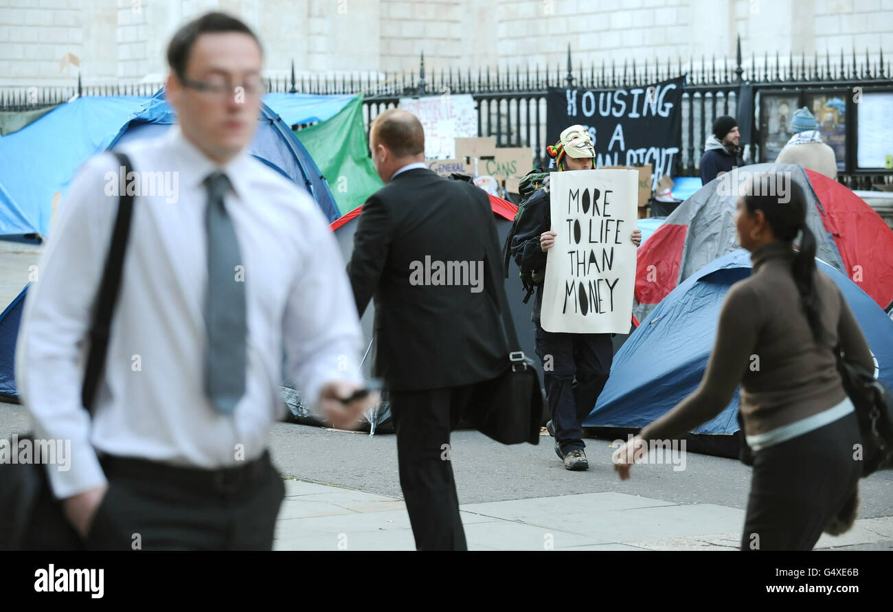 Büroangestellte passieren antikapitalistische Demonstranten, die vor der St Paul's Cathedral im Zentrum von London im Rahmen der "Occupy the London Stock Exchange"-Demonstration lagerten. Stockfoto