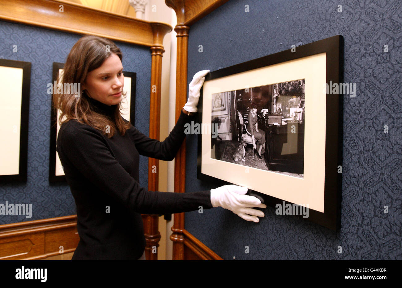 Die Mitarbeiterin der Royal Collection, Rachel Woolen, hängt mit einem ihrer Corgis, Teil der Queen, an ihrem Schreibtisch im Buckingham Palace ein Foto aus der Zeit von 1959 von The Queen: 60 Fotografien für 60 Jahre Ausstellung im Windsor Castle. Stockfoto