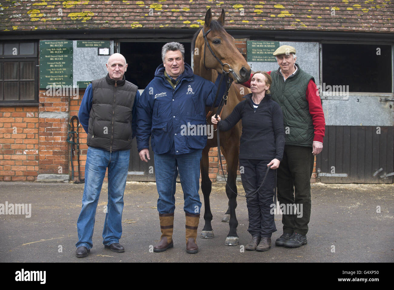 Treffen Sie sich mit seinem Trainer Paul Nicholls (zweiter links), den gemeinsamen Besitzern Ian Fogg (links) und Paul Barber (rechts) in seinen Ställen auf der Manor Farm in Ditcheat. Stockfoto