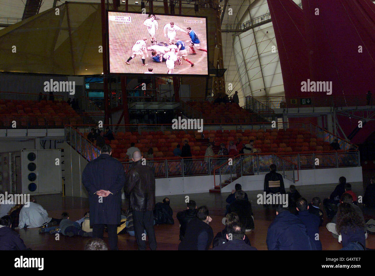 Millennium Dome Chief Executive Pierre Yves Gerbeau (links stehend), im Inneren des Dome, der die Berichterstattung über das Rugby-Spiel der sechs Nationen zwischen Frankreich und England live von Paris aus auf einer riesigen Leinwand beobachtet. Stockfoto