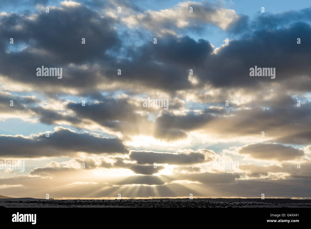 Spanien, Kanarische Inseln, Fuerteventura, Sonnenuntergang scheint durch die Wolken auf der spanischen Insel Fuerteventura Stockfoto