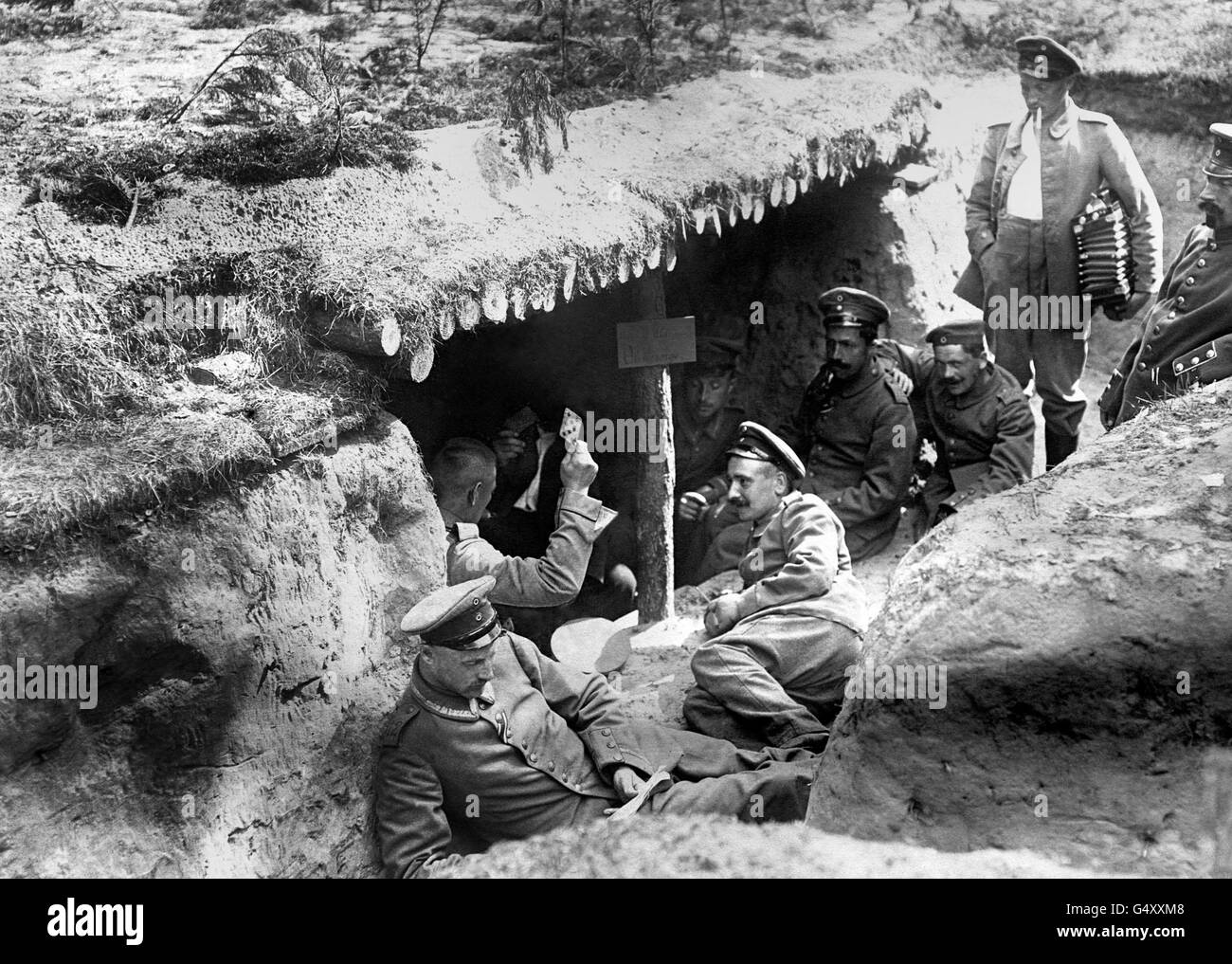 Deutsche Soldaten des 12. (2. Brandenburgischen) Regiments spielen Karten in einem Dugout in einem flachen Graben im deutsch besetzten russischen Polen während des Ersten Weltkriegs. Einer der Soldaten (ganz rechts) hält eine Ziehharmonika. Stockfoto