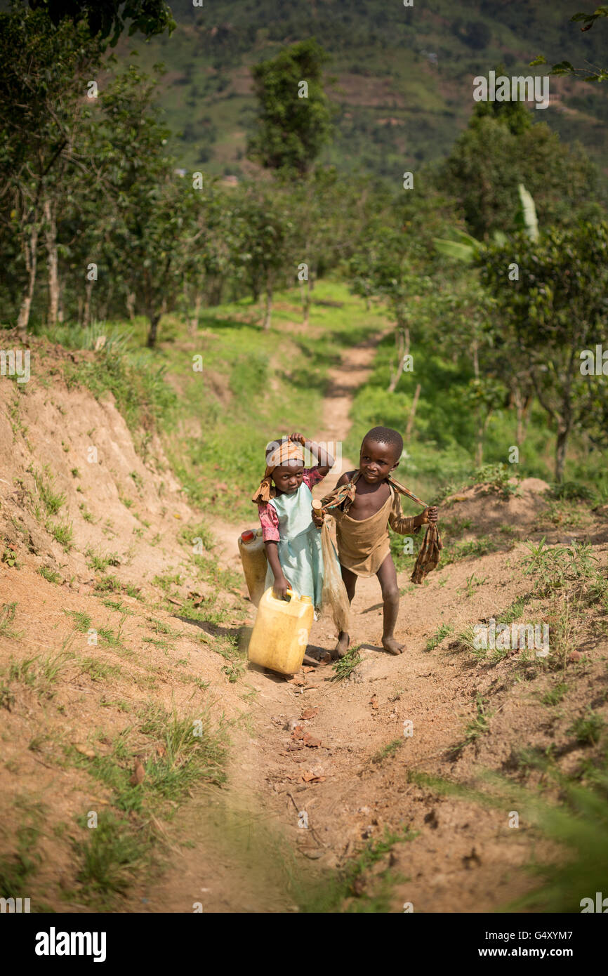 Kinder tragen Gießkannen ein Dorf Weg in Kasese District, Uganda, Ostafrika. Stockfoto