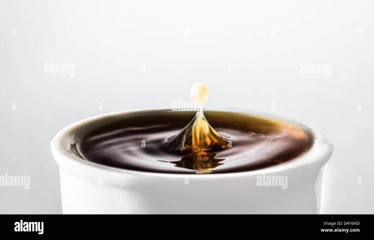 Tropfen Milch spritzt in eine Tasse schwarzen Kaffee Stockfoto