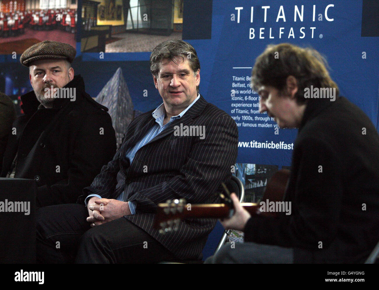 Broadcaster Peter Curran (links) mit Belfast Dramatiker Dan Gordon (Mitte) hören Bap Kennedy (rechts), spielen beim Start des Titanic Festival 2012, in den ehemaligen Harland und Wolff Salon in Belfast. Stockfoto