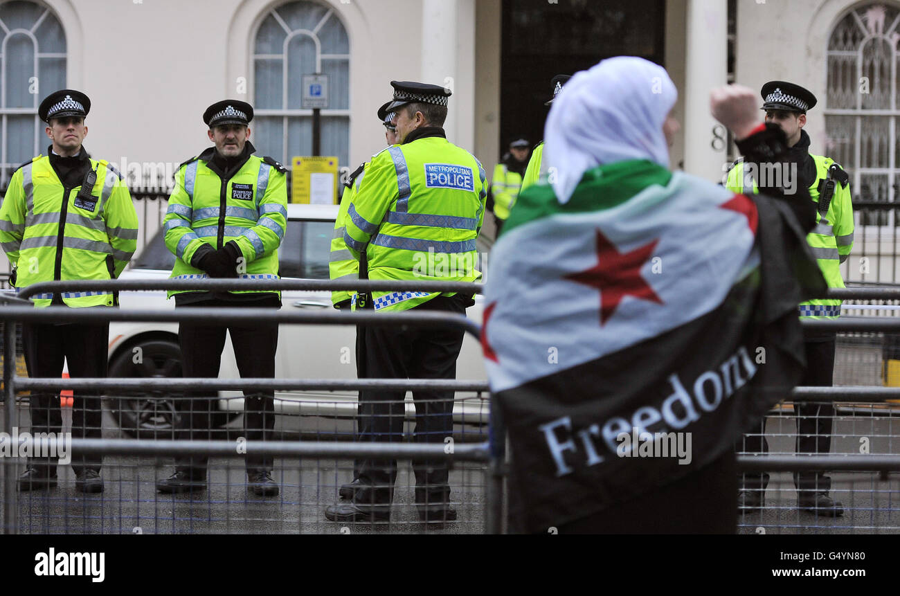 Eine Frau, die in eine syrische Flagge gehüllt ist, als Demonstranten vor der syrischen Botschaft auf dem Belgrave Square im Zentrum von London über den eskalierenden Konflikt in Syrien demonstrieren. Stockfoto