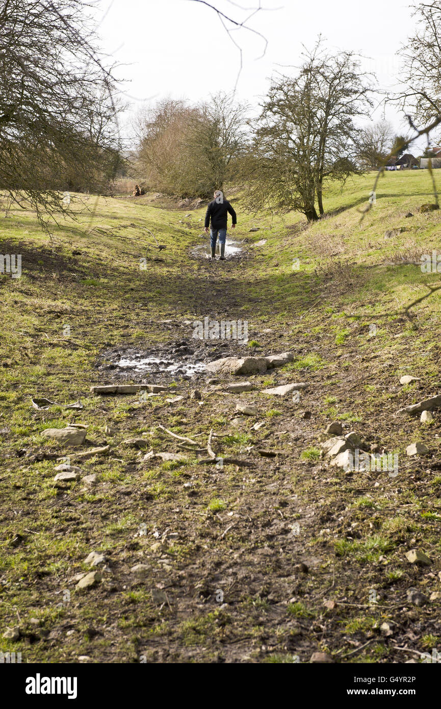 Simon Evans von Thames Water wandert auf einem kleinen schlammigen Fleck, wo der Fluss Kennet normalerweise entlang Feldern in der Nähe des Dorfes Lockeridge, westlich von Marlborough, fließt. Stockfoto