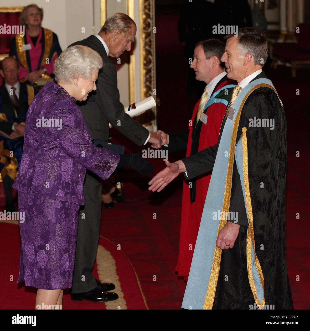 Queen Elizabeth II. Und der Duke of Edinburgh verleihen Professor Sir Peter Gregson (rechts) und Professor Dennis McCance von der Queen's University Belfast im Buckingham Palace im Zentrum von London einen Royal Anniversary Prize for Higher and Further Education. Stockfoto