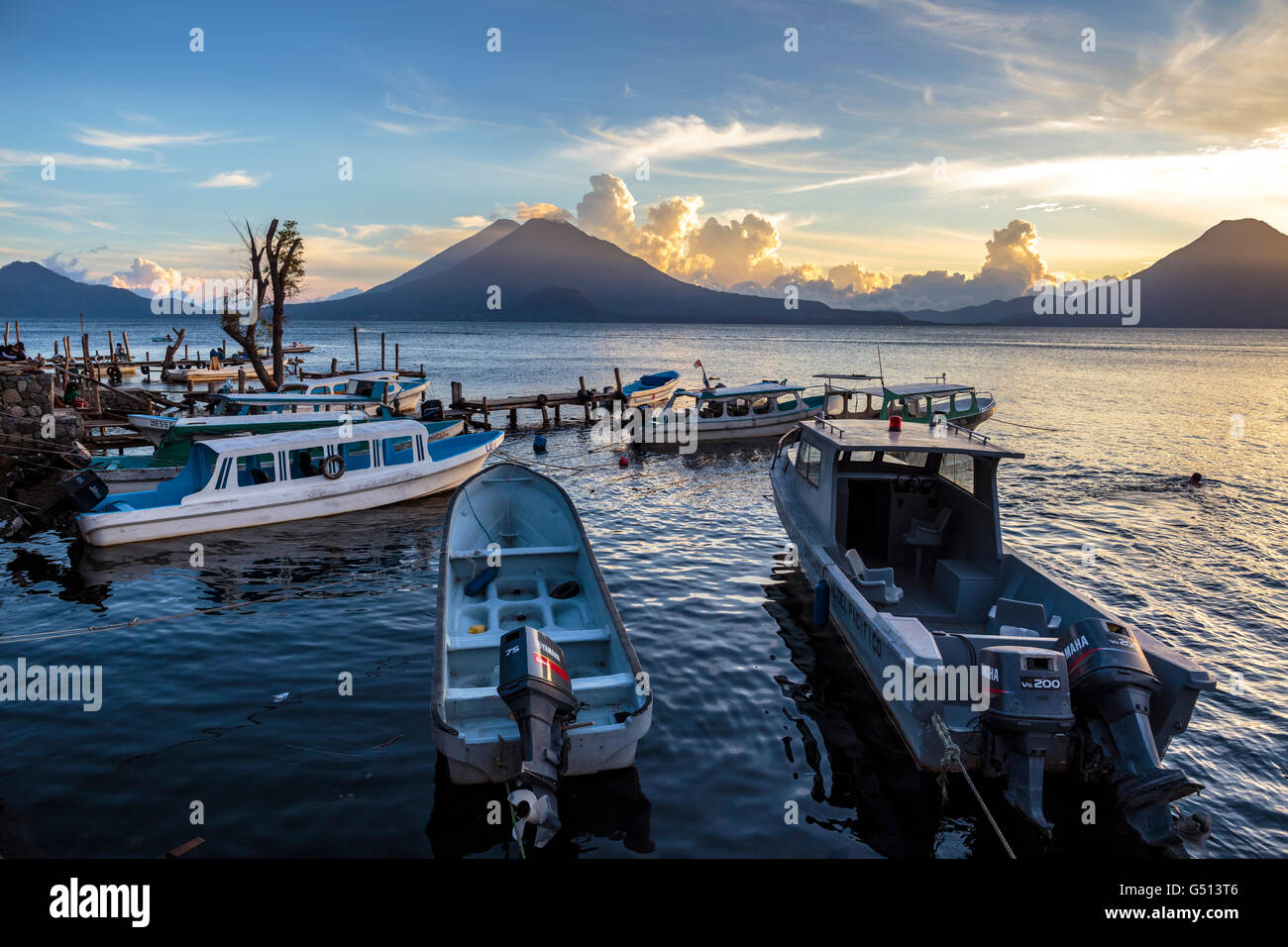 Sonnenuntergang über die Vulkane der Lago de Atitlán in Guatemala und Wasser taxis Sit festgemacht an den Docks des Ferienortes Panajachel Stockfoto