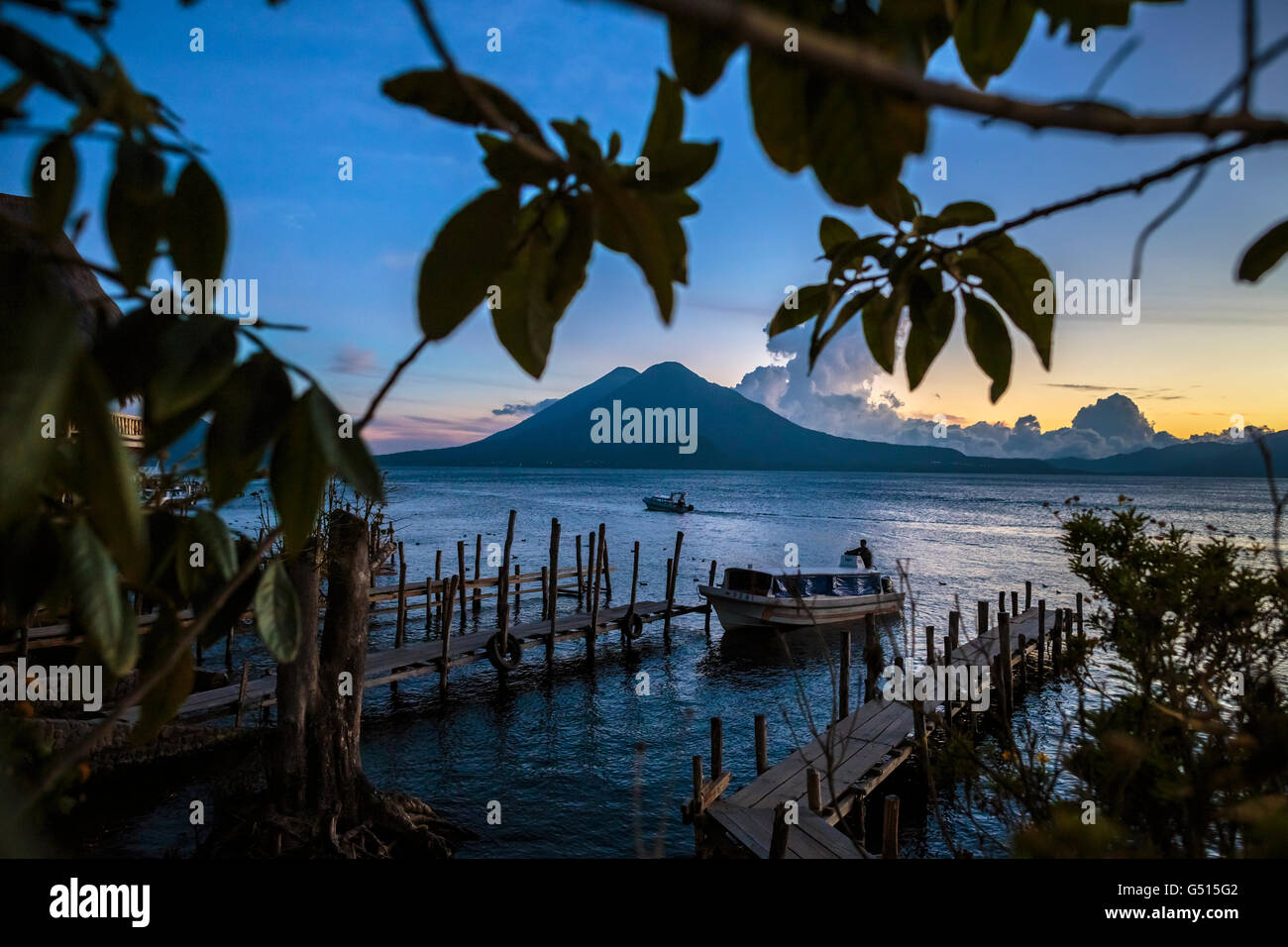 Die Sonne geht über Lago de Atitlan in Guatemala, und die letzten Wassertaxis bringen Touristen zu den Docks in Panajachel in der Abenddämmerung. Stockfoto