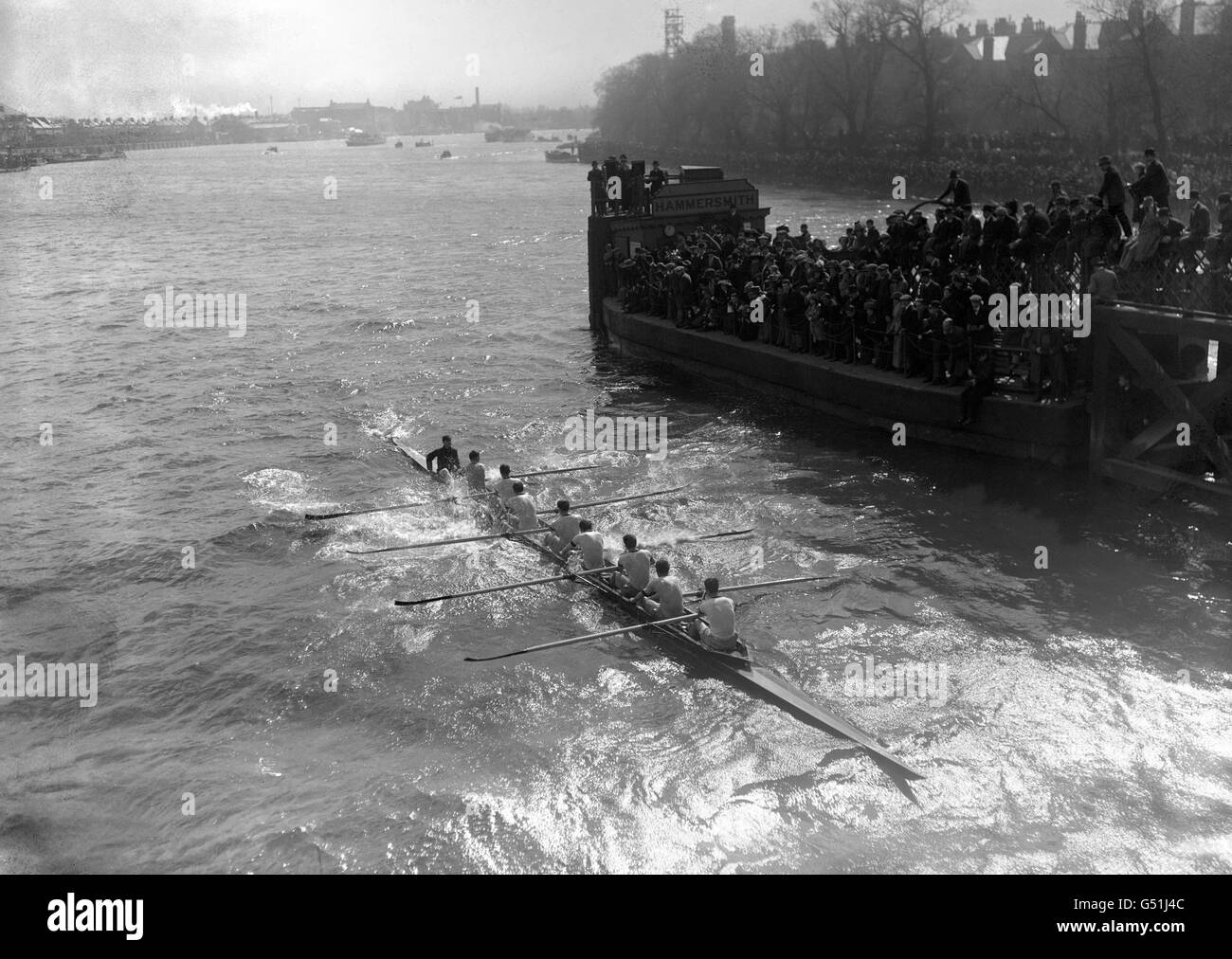 Die Oxford-Besatzung, die unter der Hammersmith Bridge in rauem Wasser vorbeikam. Das University Boat Race von 1912 ist einzigartig in der Geschichte des Rennens, da es die einzige Gelegenheit ist, wenn beide Crews gesunken sind. Stockfoto