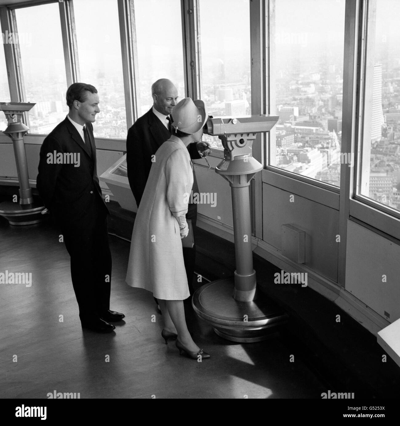 Queen Elizabeth II blickt durch ein Teleskop auf den Buckingham Palace, während sie den Post Office Tower, Londons höchstes Gebäude, besucht. Mit ihr (l-r) Anthony Wedgwood Benn, Postmaster General, und Mr. A.B Harnden, Director London Telecommunications Region. Stockfoto
