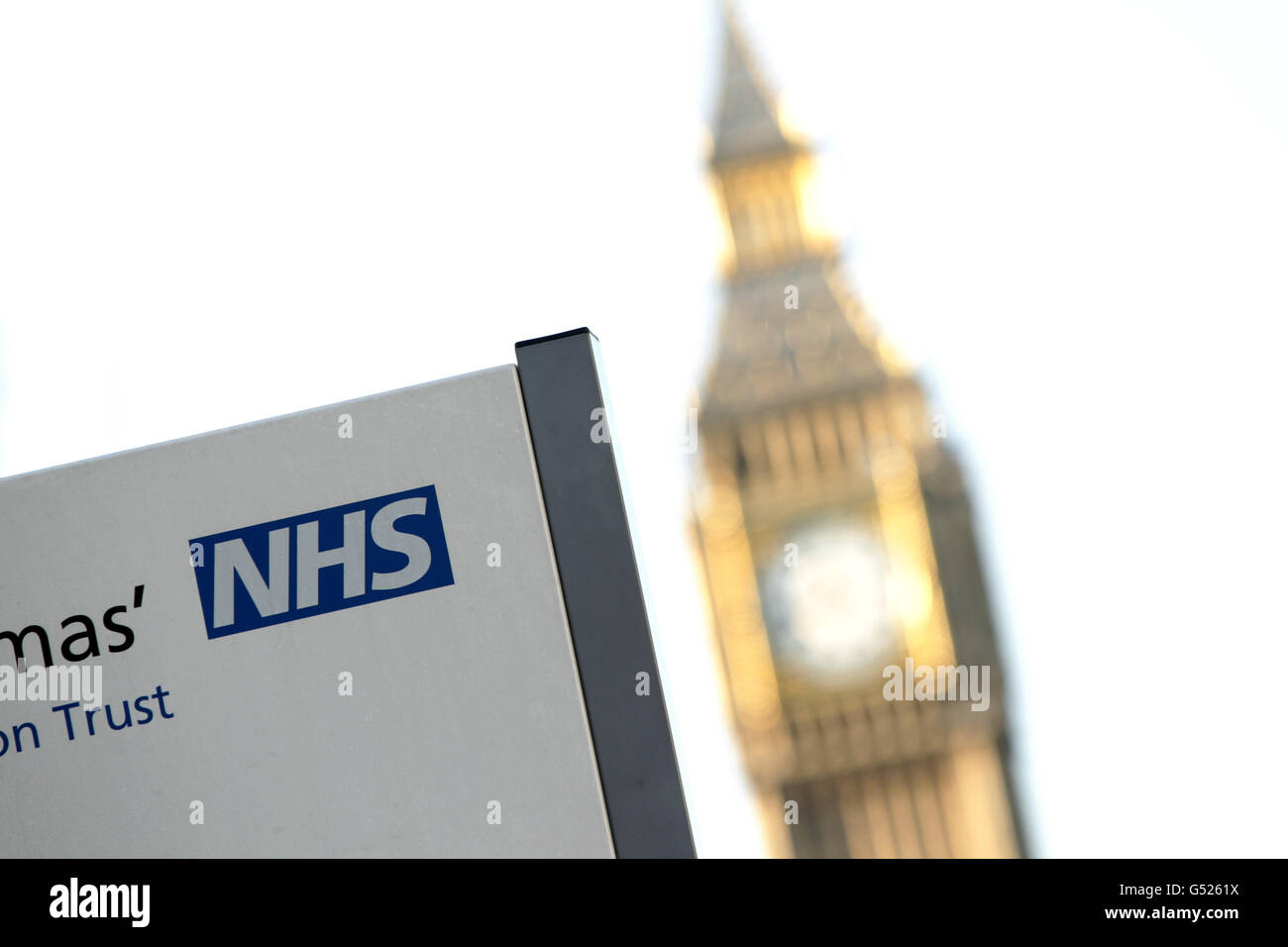 Ein NHS-Schild am St. Thomas' Hospital, mit Big Ben im Hintergrund, in Westminster, im Zentrum von London Stockfoto