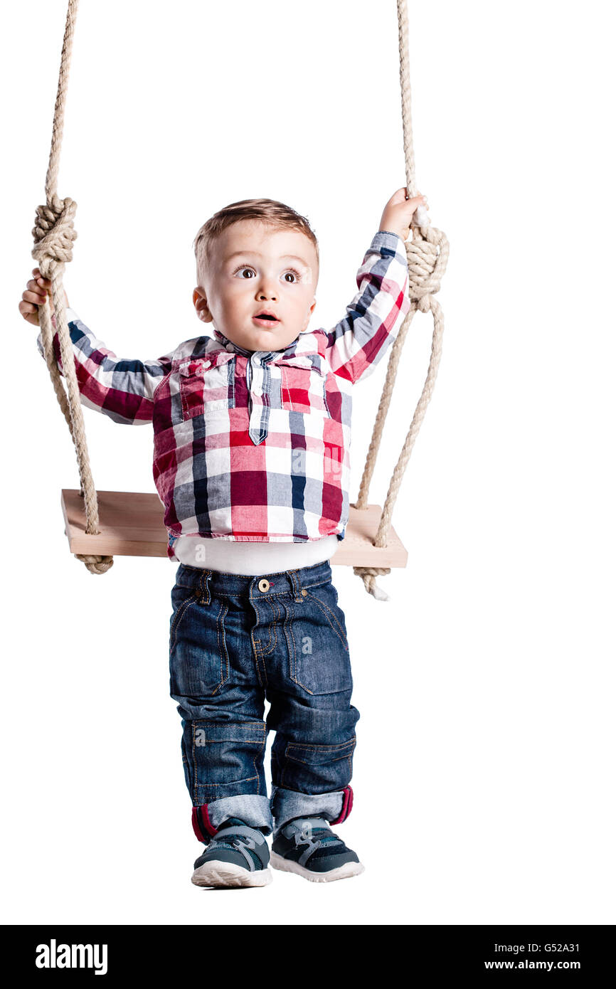 glückliche kleine Junge schwingt auf einer Holzschaukel Stockfoto