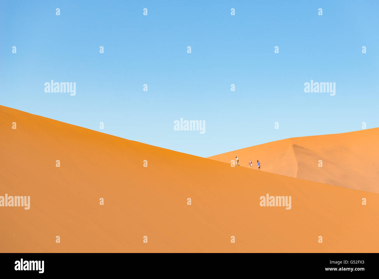 Namibia, Hardap, Sossusvlei, drei Personen zu Fuß entlang der Big Daddy Düne, Big Daddy Düne, nach Sonnenaufgang Stockfoto