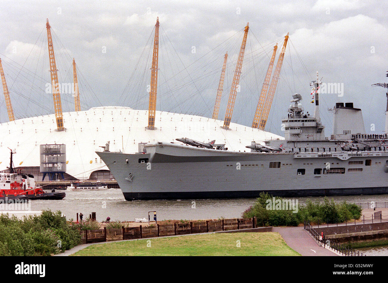 Der Flugzeugträger HMS Invincible passiert den Millennium Dome an der Themse in Greenwich, London, und geht nach einer 24 Millionen Umbauarbeiten, die 2000 fertiggestellt wurde, auf See. Unbesiegbar hat vor kurzem Aufgaben im Kosovo ausgeführt. * ...als Teil der NATO-Truppen in der Adria. Das Re-FIT hat es mit einem verlängerten Flugdeck und einem hochmodernen Computersystem ausgestattet. Königin Elisabeth II., die das Schiff am 13/07/00 besuchte, startete es 1977. Stockfoto