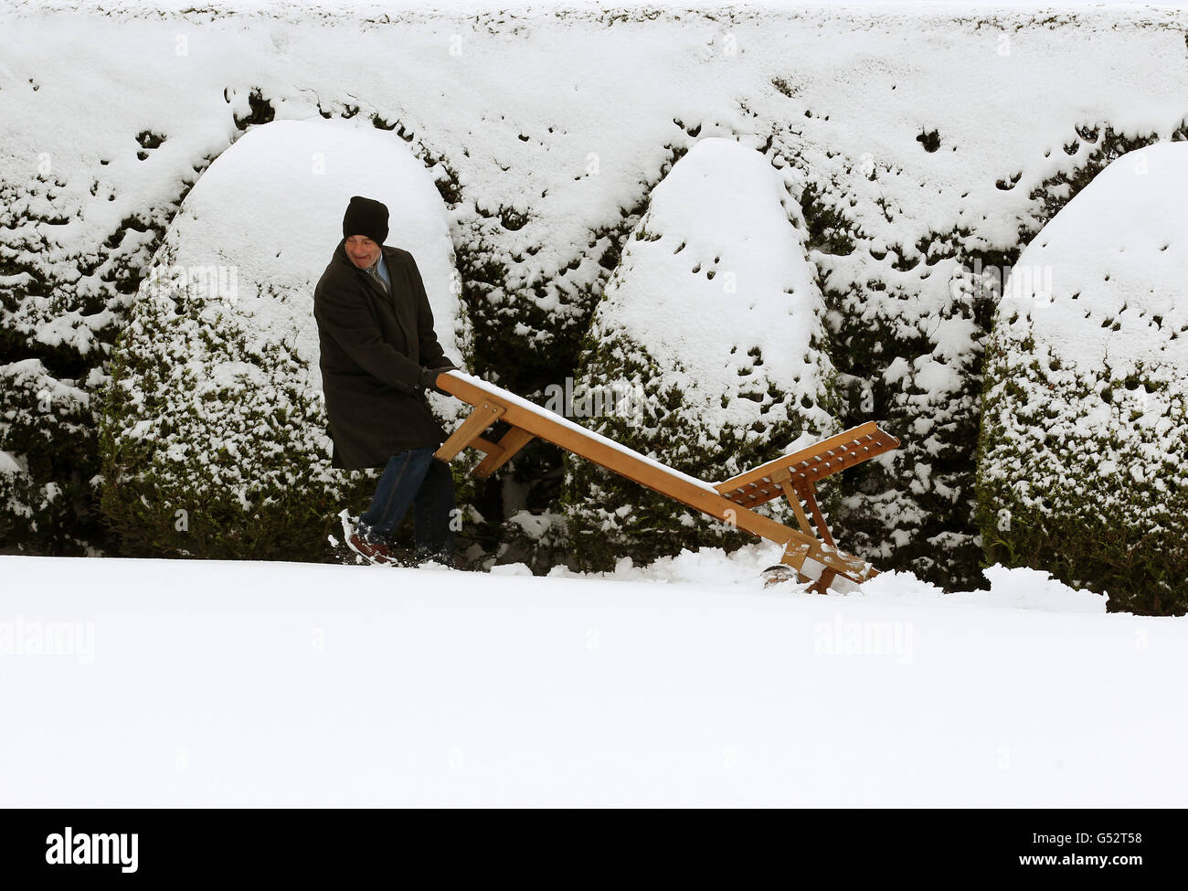 Dan Cascarino bewegt seine schneebedeckte Sonnenliege, die er während der Hitzewelle der letzten Wochen in seinem Haus in der Nähe von Auchterarder benutzte, als innerhalb von vier Stunden in Teilen Schottlands über Nacht mehr als sechs Zoll Schnee fielen, als sich eine arktische Wetterfront auf Großbritannien niederbohrt. Stockfoto
