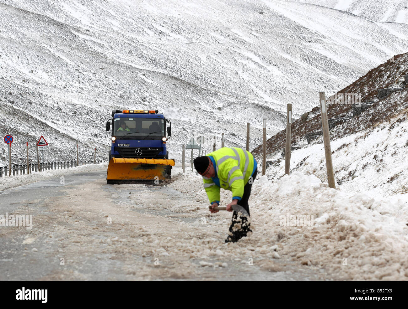 Ein ratsarbeiter und Grinter aus Perth und der Kinross-Rat schnapp sich an der Eis bedeckten A93 am Spittal von Glenshee in den Cairngorms ab, nachdem sie gestern wegen Schneefalls geschlossen war. Stockfoto