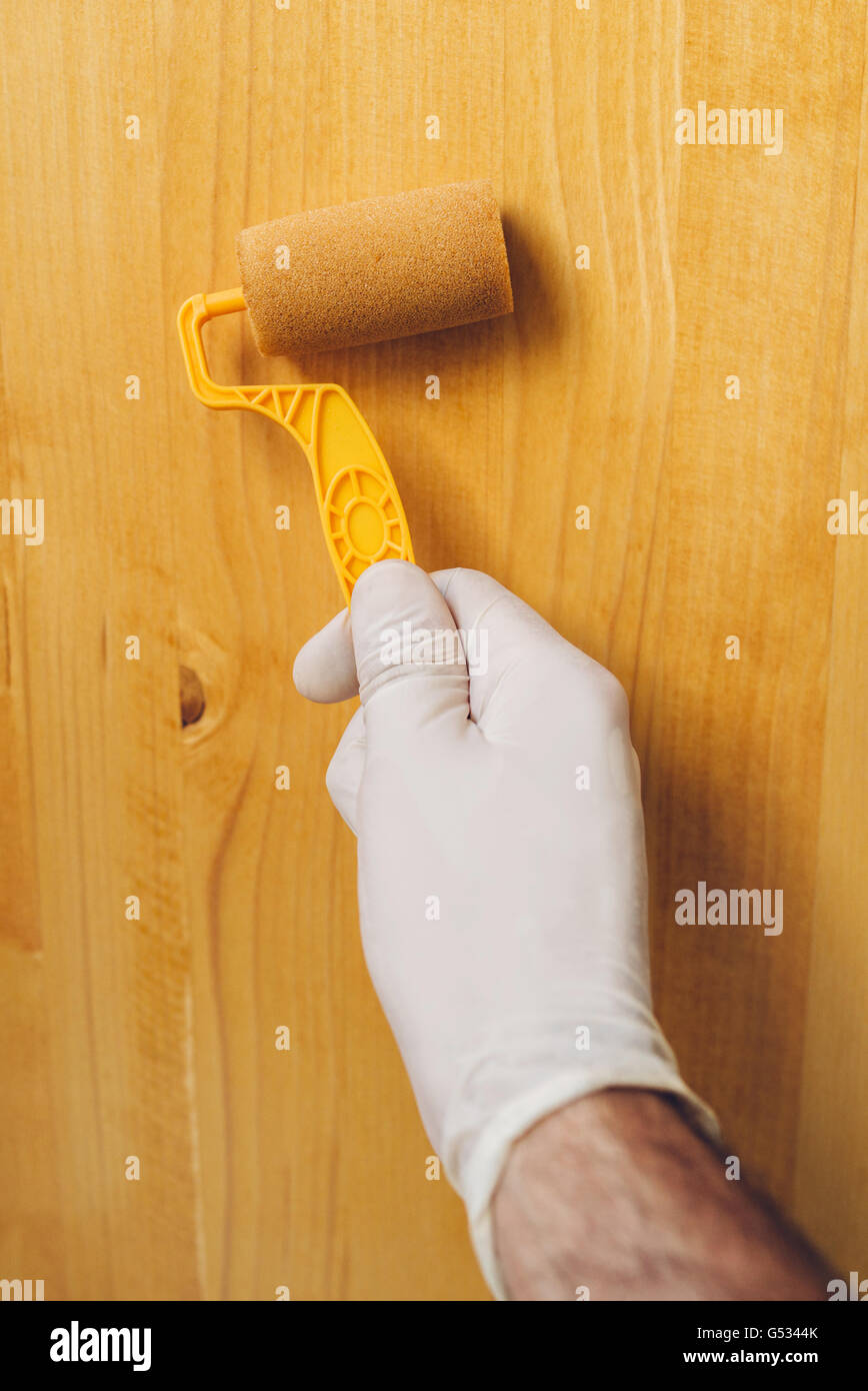 Hand mit Farbe Walze auftragen Acryllack auf Holzbrett, nicht giftige Wasser basierte Holz Lack Stockfoto