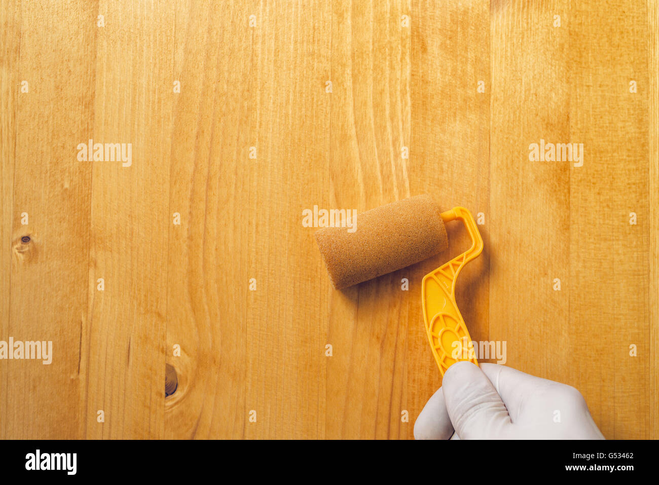 Hand mit Farbe Walze auftragen Acryllack auf Holzbrett, nicht giftige Wasser Basis Lack Holz für Möbel Stockfoto