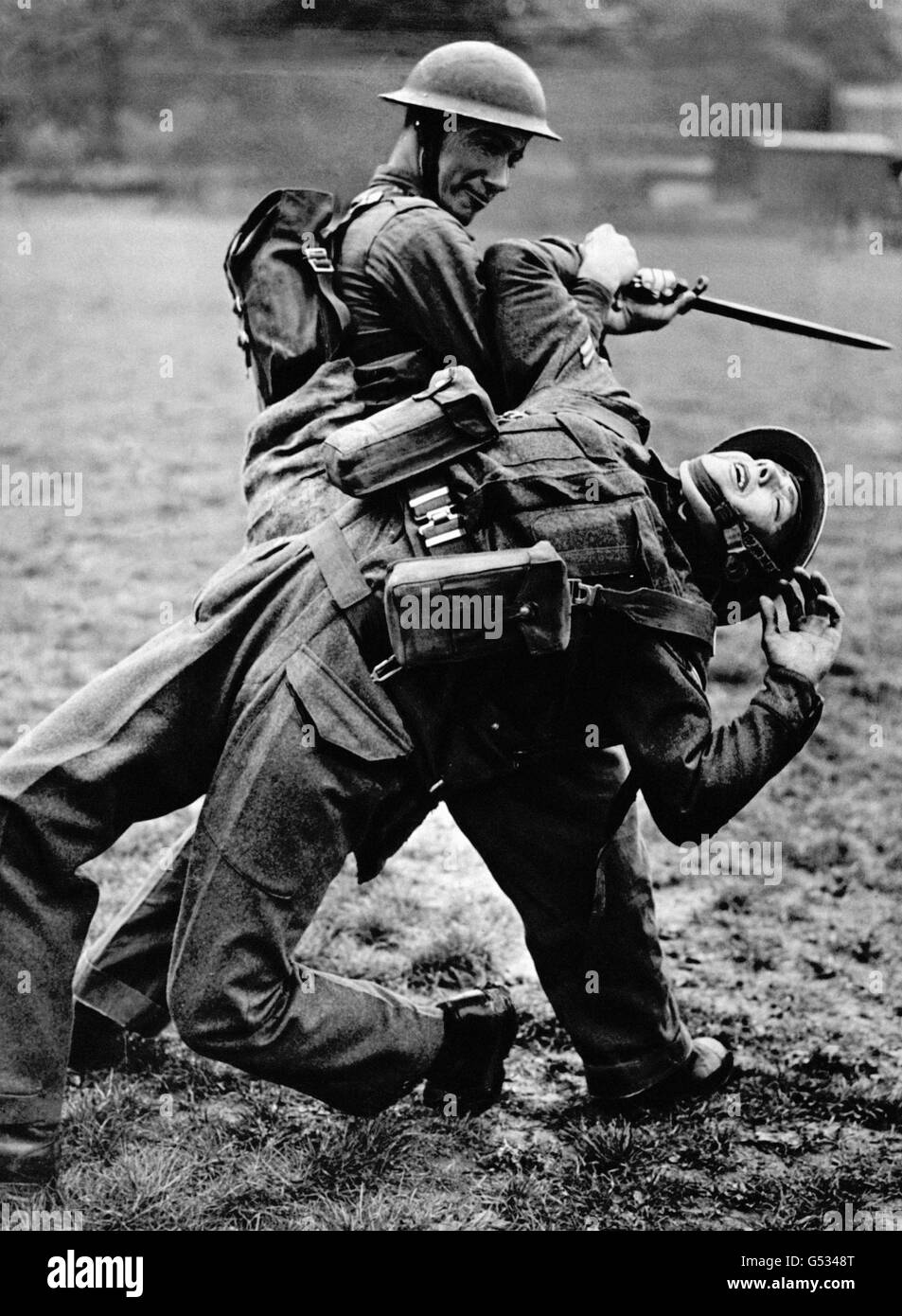 Zwei britische Soldaten genießen während des Zweiten Weltkriegs eine Lektion im unbewaffneten Kampf. Ein Soldat versucht, den anderen zu entwaffnen, der ein Bajonett hält. Stockfoto