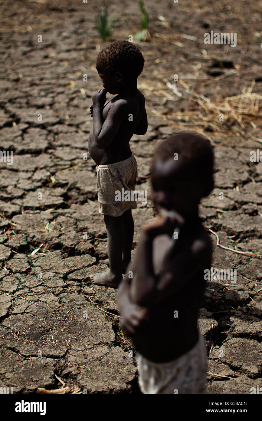 Zwei kleine Jungen stehen im Doro-Flüchtlingslager in Bunj, Maban, im Bundesstaat Upper Nile Blue Nile im Nordosten des Südsudans, auf ausgetrocketer Erde. Afrika.die Region litt vor kurzem unter schweren Zusammenstößen zwischen Nord- und Südsudan, die zu Zehntausenden von Menschen in Flüchtlingslager wie Doro und JamMan und Hunderten von Todesfällen durch die Bombardierung von Dörfern und Zusammenstöße zwischen rivalisierenden bewaffneten Gruppen geführt haben.in den riesigen Flüchtlingslagern töten Krankheit und Unterernährung Die jungen, schwachen und älteren Menschen und mit den Regenfällen drohen Ende april das Leid verschlimmern.Ziel, die irische Hilfsorganisation im Sudan Stockfoto