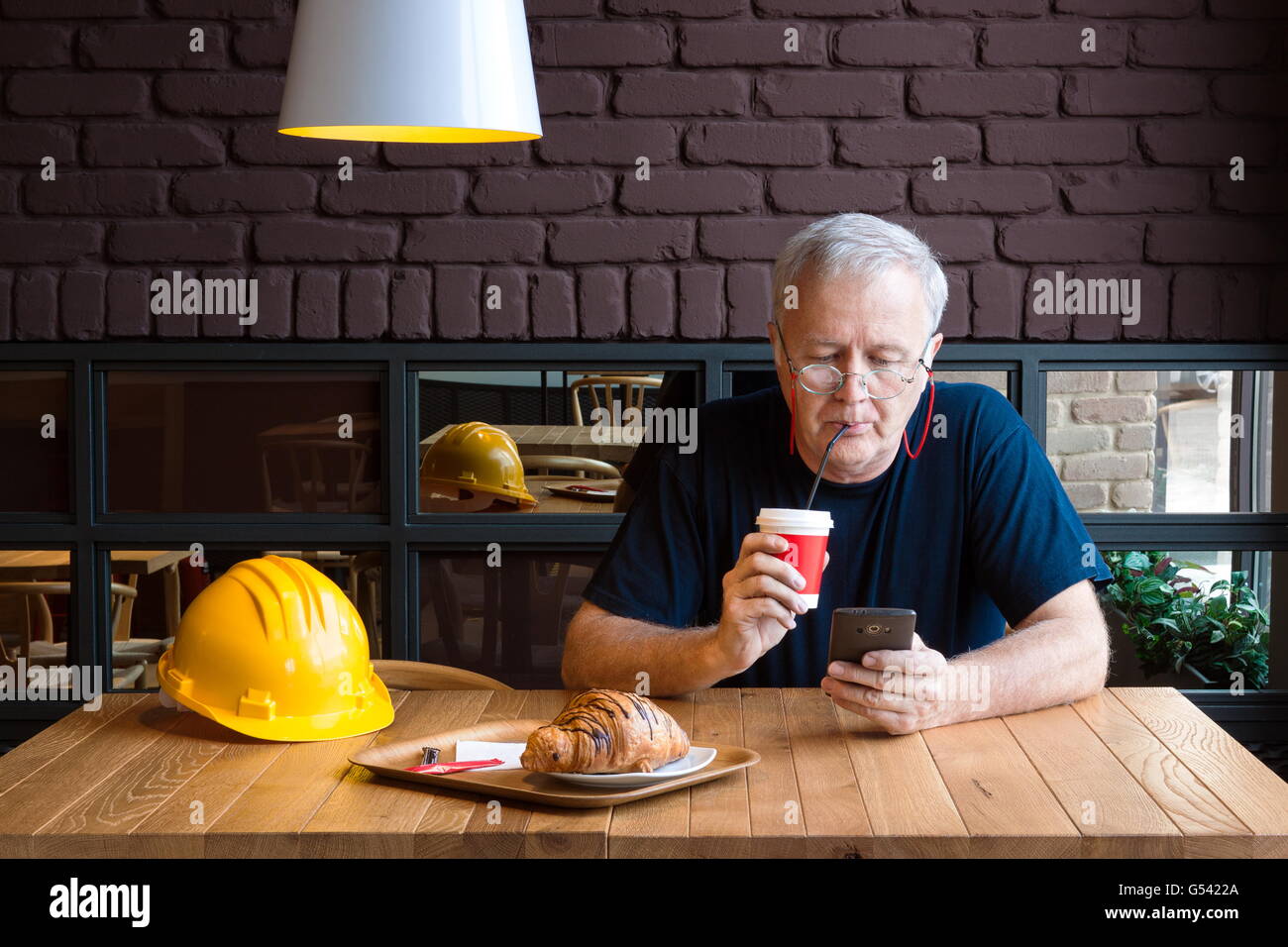 Leitender Bühnenmeister Erfrischung Pause, Kaffee trinken und überprüft seine Telefon Stockfoto