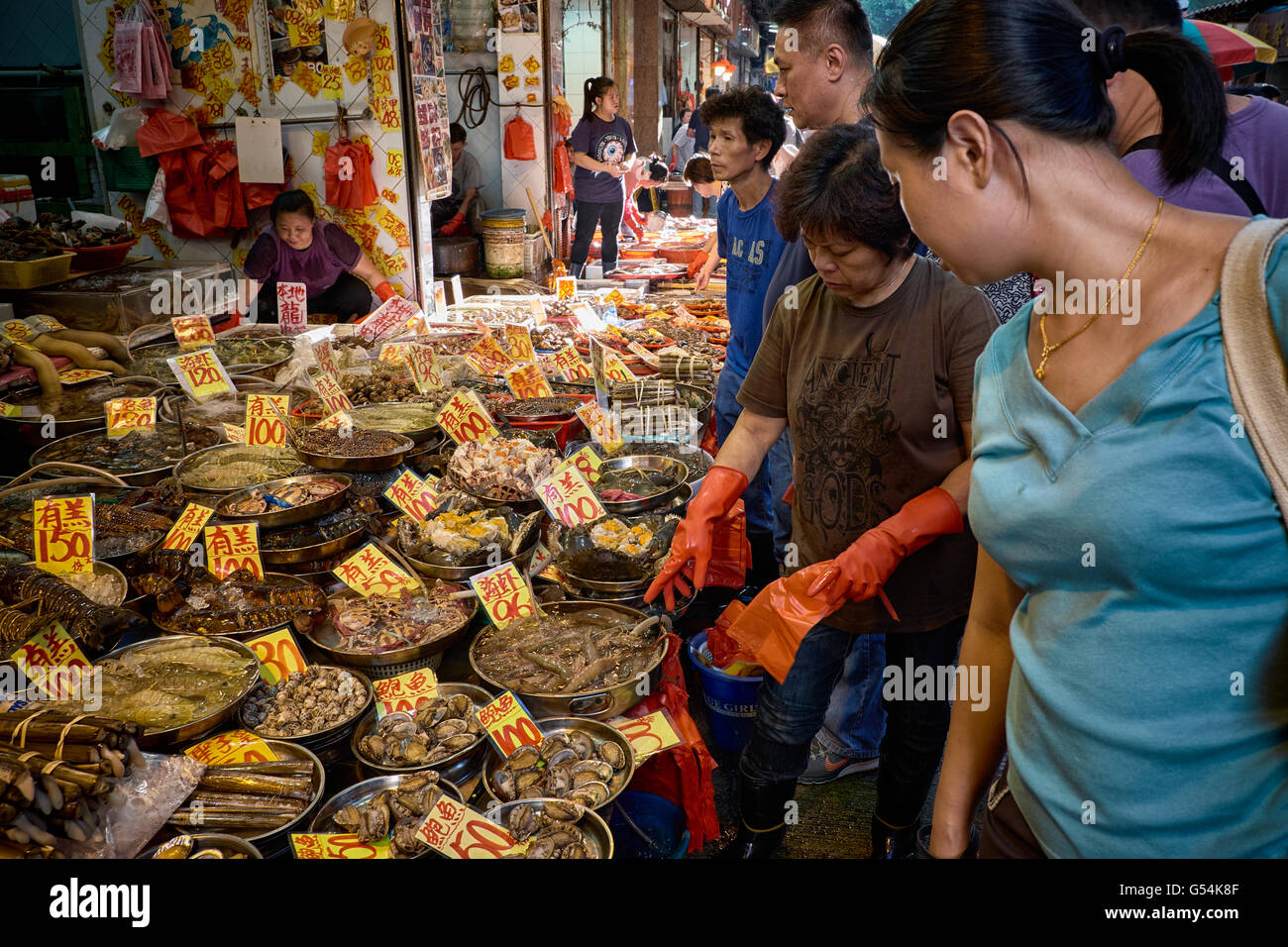 Shopper versammeln und Einkäufe in einer Schale Fisch Anbieter Stall auf Nelson Street in Mongkok, Hong Kong. Stockfoto