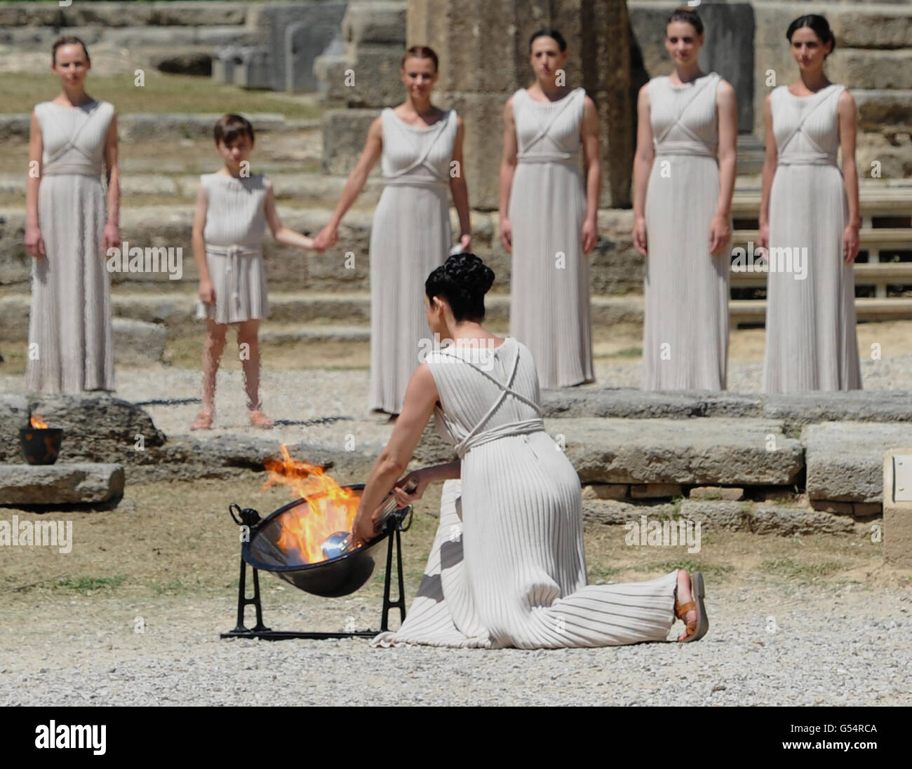 Die olympische Flamme wird von einer Schauspielerin angezündet, die als hohe Priesterin gekleidet ist, und benutzt einen parabolischen Spiegel, um die Strahlen der Sonne zu reflektieren, während einer Probe für die morgige Zeremonie, Was der Welt signalisiert, dass der Countdown zu den Spielen von London 2012 begonnen hat, am Tempel von Hera in Olympia, Griechenland, wo die antiken Olympischen Spiele stattfanden. Stockfoto