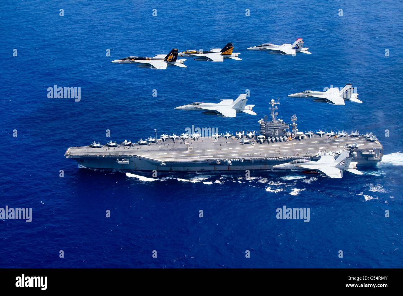 US Navy F/A-18 Hornet-Kampfflugzeuge fliegen in Formation über die Nimitz-Klasse nuclear-powered Supercarrier USS John C. Stennis bei dual Operationen mit der USS Ronald Reagan Fördermaschinegruppe 18. Juni 2016 in der Philippinensee. Stockfoto