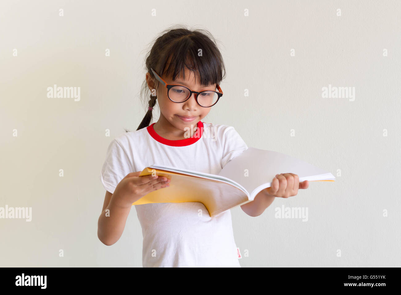 Asiatische Mädchen Kind ist lustig, ein Buch lesen Stockfoto