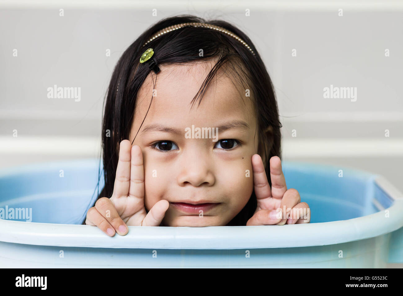 Schöne kleine Asiatin spielt in blauen Korb Stockfoto