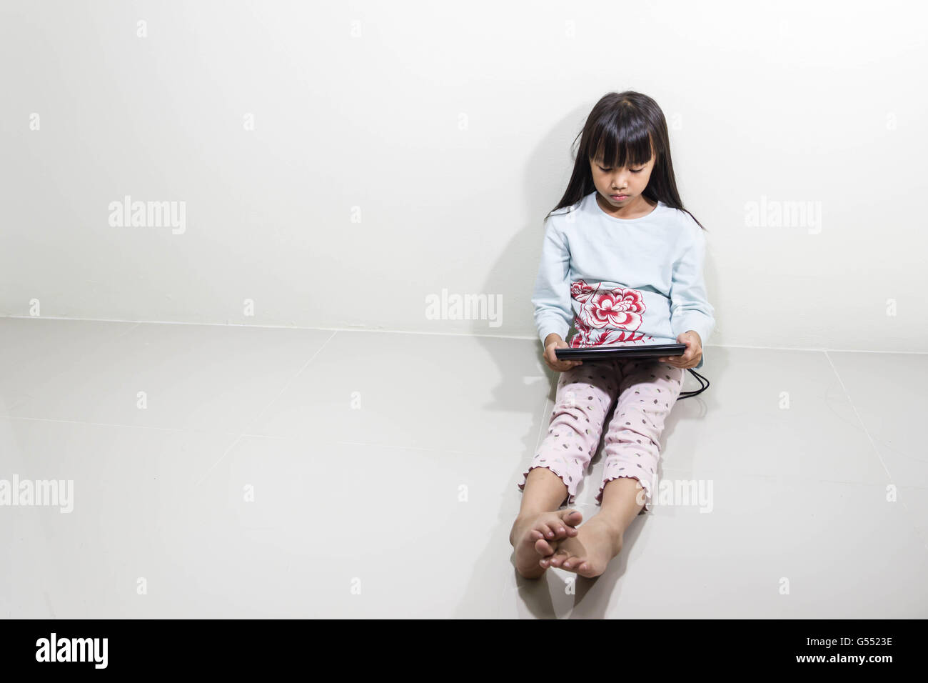 Kinder mit Tablet-PC sitzen auf dem Boden - Technologie und Kinder Konzept Stockfoto
