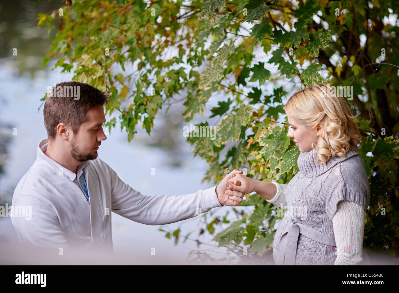 Glückliche schwangere Frauen und ihr Mann während der Wanderung mit einem Mann in der Nähe des Sees Stockfoto Glückliche schwangere Frauen und ihr Mann während der Wanderung mit einem Mann in der Nähe des Sees Stockfoto