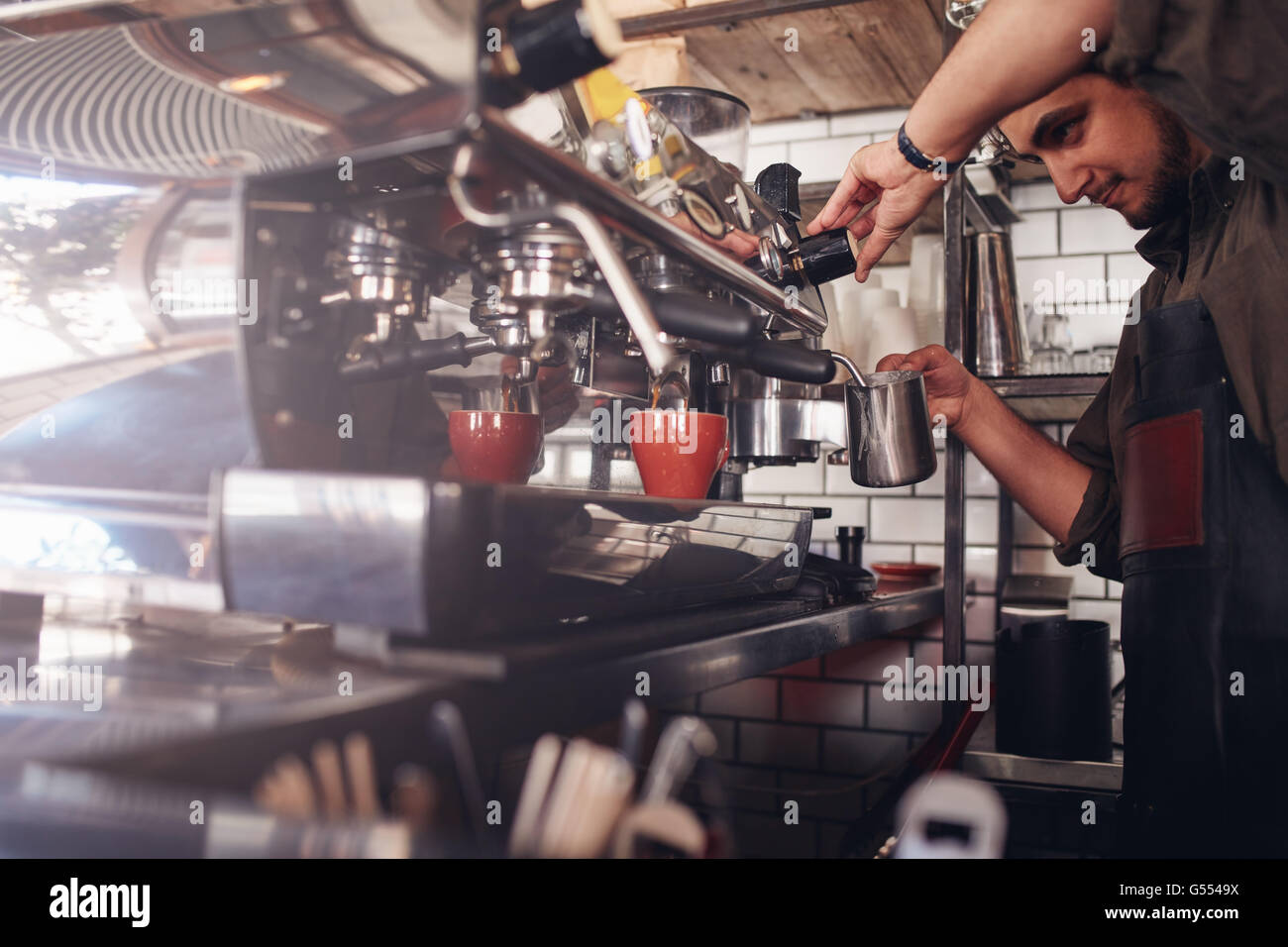 Schuss von Barista mit einer Kaffeemaschine, um eine Tasse Kaffee zu machen. Cafe-Arbeiter eine Kaffeezubereitung. Stockfoto